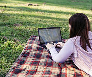 Angela Rodgers using laptop on picnic blanket